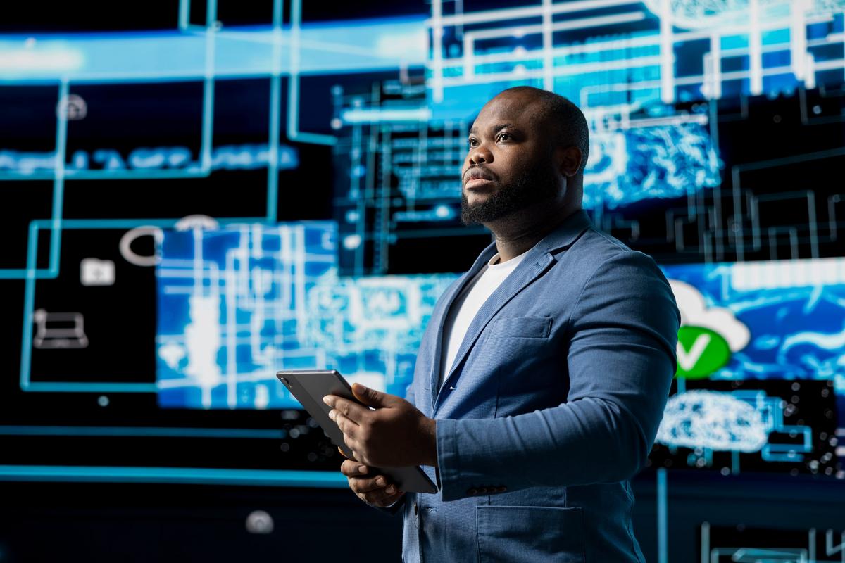Man in a suit holding a tablet before a wall of glowing network diagrams.