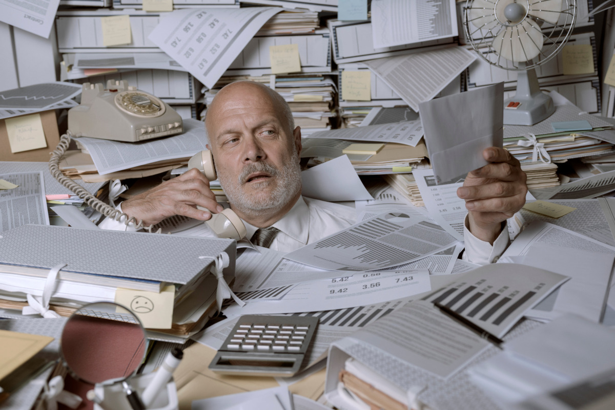 Overwhelmed businessman in paper clutter